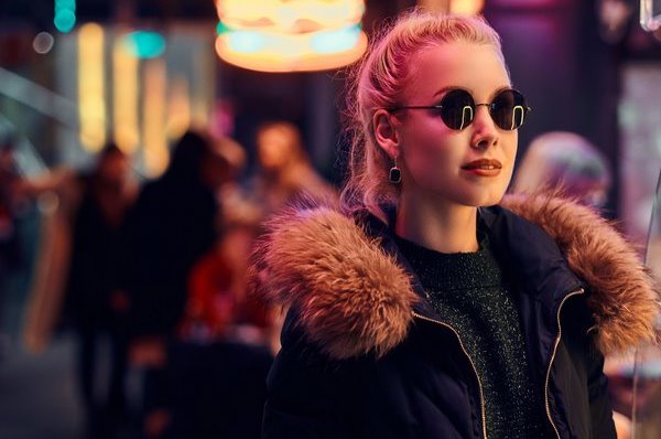 A sensual girl standing in the night on the street. Illuminated signboards, neon, lights.